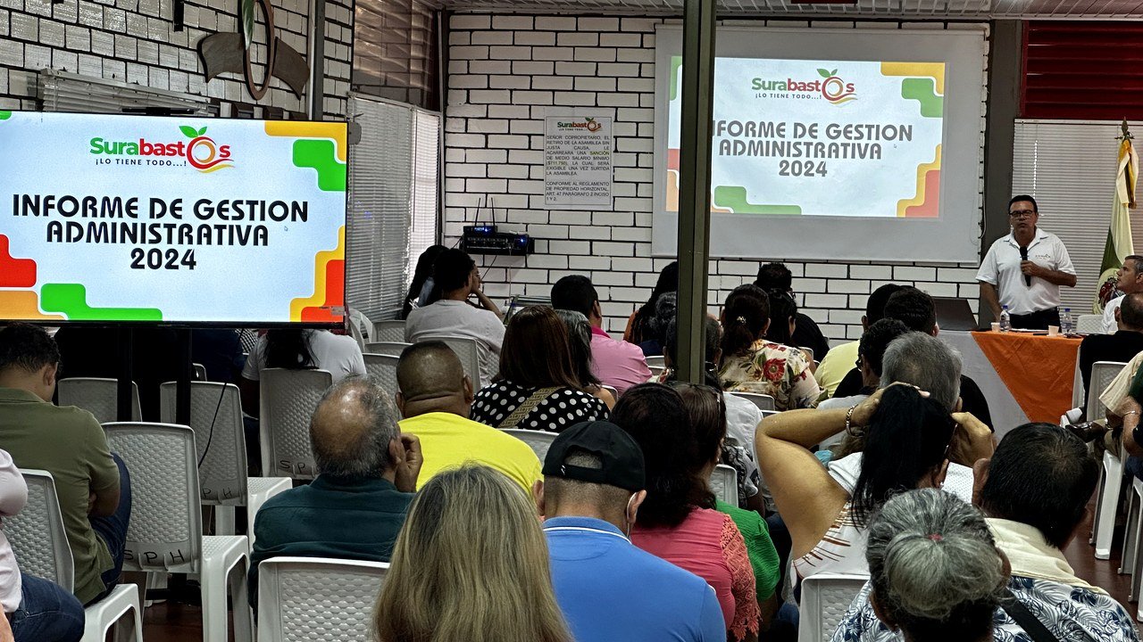 Asamblea Surabastos en Neiva con asistentes, pantalla de apoyo y presentacion institucional.